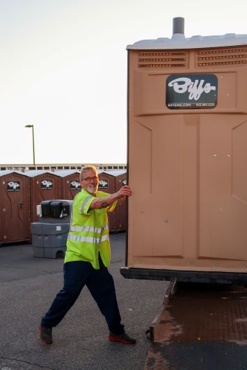 Portable Restroom Delivery Services | Biff’s Biff's employee loading a portable restroom onto a service truck for delivery to a construction site or special event in Minnesota.